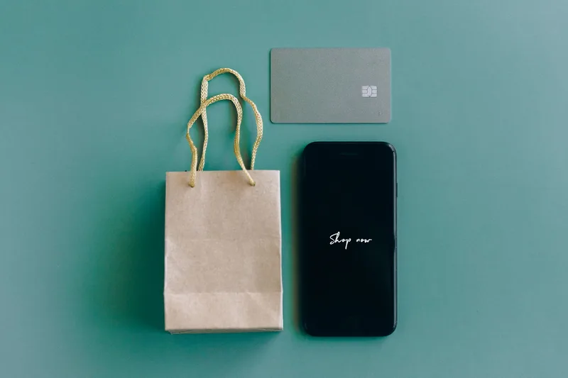 A phone, payment card, and shopping bag used to compare GCC ecommerce platforms