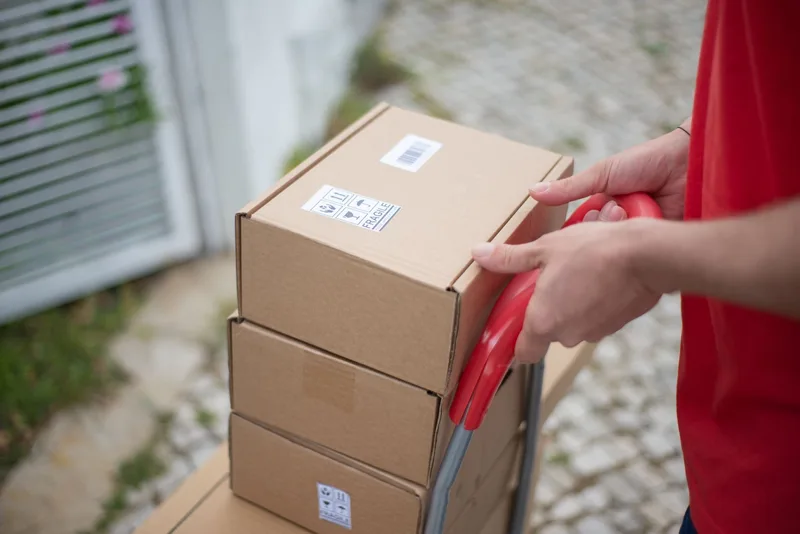 Trolley loaded with stacked cardboard boxes representing the shipping and logistics side of dropshipping operations